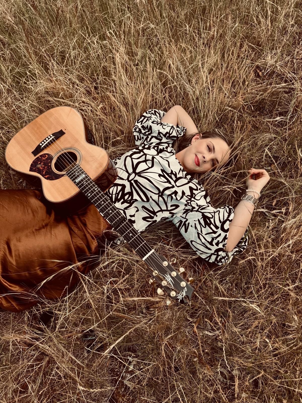 Ruby Holden playing guitar in golden hour light