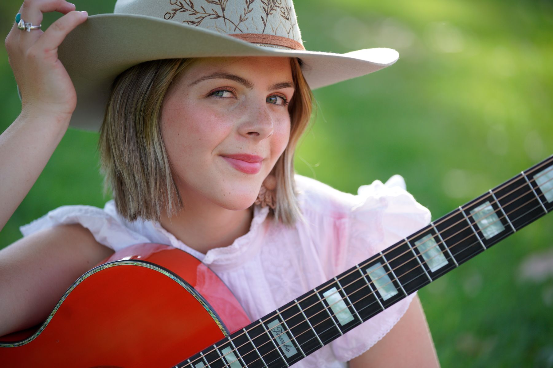 Ruby Holden with red guitar outdoors