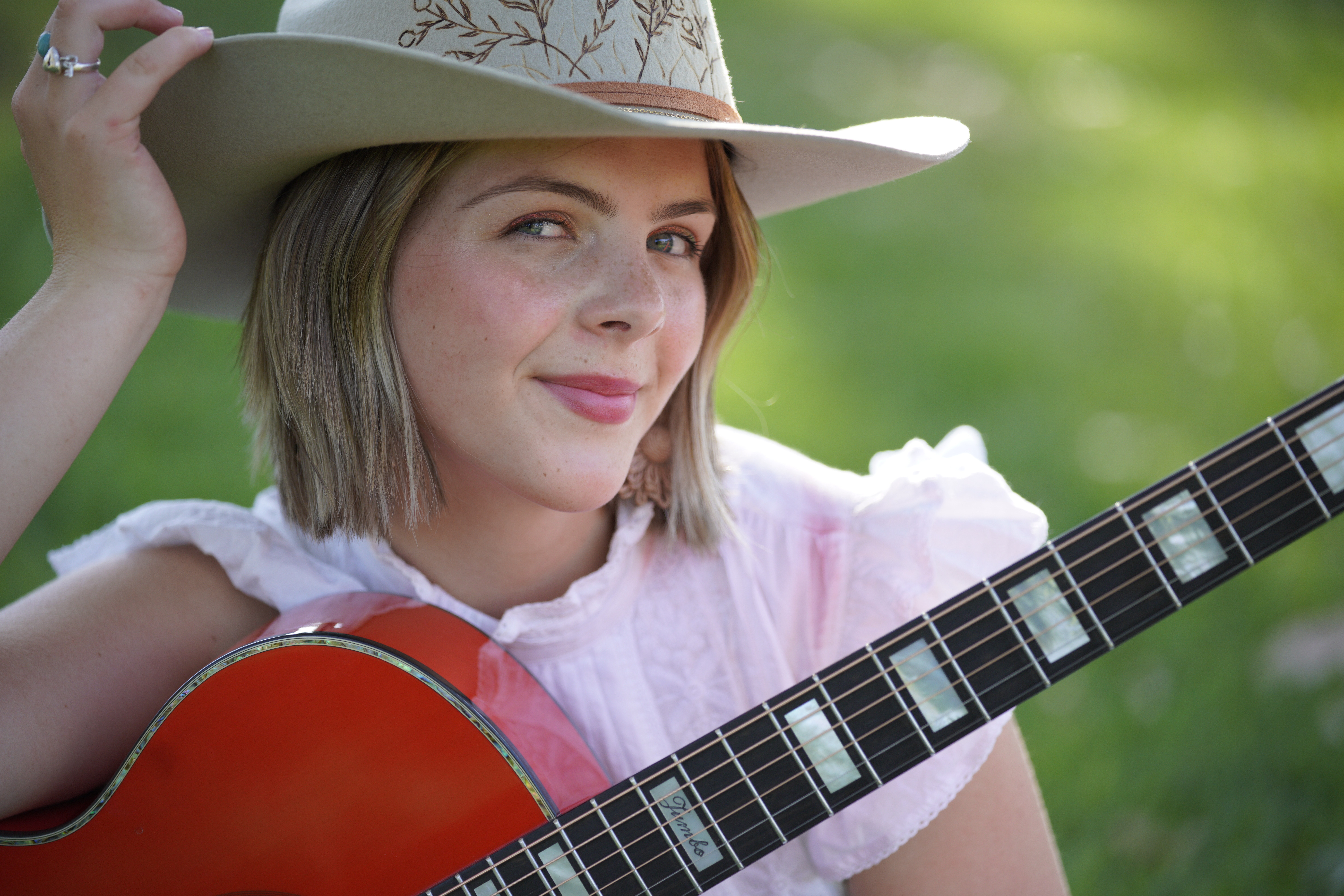 Ruby Holden with red guitar outdoors