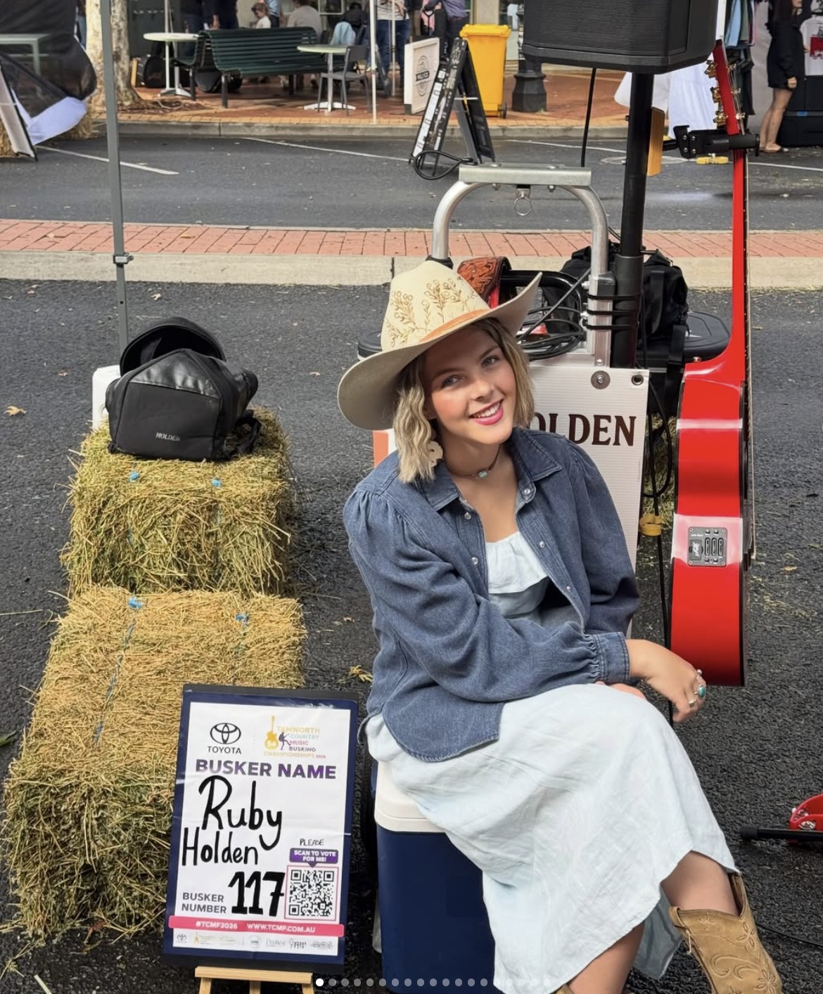 Ruby Holden with red guitar and cowboy hat performing outdoors